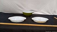Overview of three vintage Pyrex opal-glass pieces on black backdrop