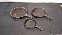 Three cast iron skillets arranged on black surface