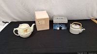 Overview of all three items: boxed Farberware kettle, floral ceramic teapot, grey speckled teapot