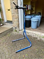 Full view of blue Park Tool PCS-1 repair stand set up on driveway