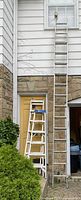 Both ladders leaning against house showing full height and relative size