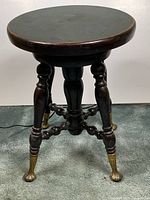 Full view of stool from front showing seat, legs, brass feet