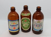 Front view of three amber stubby beer bottles showing labels