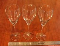 Front view of three clear crystal wine glasses with ruler for scale
