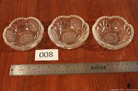 Three cut crystal dishes on table with ruler showing scale