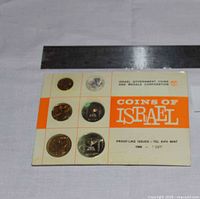 Front of folder showing title and two coins