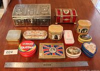 All twelve tins arranged on table with ruler for scale