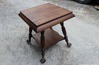 Angled view of entire table highlighting lower shelf and claw feet