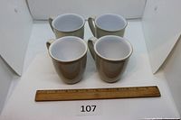 Four Denby linen mugs front view beside ruler