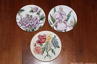 Three of the Fitz & Floyd plates showing floral designs and gold rim