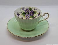 Tea cup on saucer showing mint green exterior and violet interior design