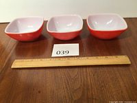 Three red square Pyrex bowls top view with ruler showing size