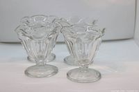 four clear pressed-glass sundae cups front left view
