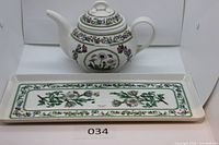 Teapot with lid front view beside tray