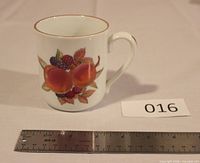 Front view showing peach and berry motif, gold rim, scale ruler