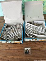 Two open boxes with many individually packaged square magnets plus one loose magnet in front