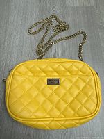 Front view of yellow quilted purse with chain strap displayed