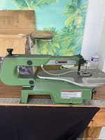 Side view of green Central Machinery 16" scroll saw on table