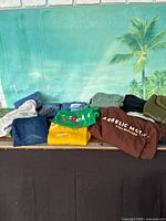 Overview of folded apparel showing sweatshirts, jeans, sweaters