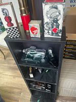 Shelf showing boxed chess piece and lantern bottles, red cylindrical bottle, green car bottle, bird bottle, small and large car decanters