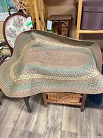 Full view of oval braided carpet draped over chair