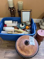 Overview of tote with assorted candles, holders, frame, canister lid visible