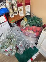 Shelf with Santa figurines, tinsel garlands, wreath form, red ornaments, textiles visible