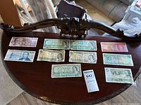 Overview of all ten banknotes laid on a small wooden table