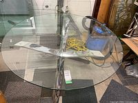 Full view of round glass tabletop on chrome X-base