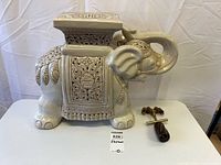 Side view of ceramic elephant pedestal with corkscrew beside for scale