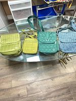 Four Lug crossbody purses on glass table showing overall colours and styles