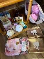 Group shot showing perfumes, soaps, lotion, bath bomb, bath puffs, cosmetic bags and tray