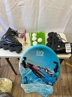 Inline skates, X Games sled, plastic rods, balls, medal on table