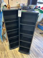 Front view of both black shelving units showing adjustable shelves