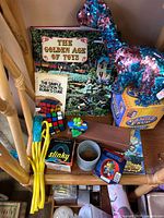 Shelf view showing books, Ty dinosaur, Rubik's Cube, Slinky, skipping rope, LEGO bin