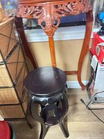 Tall carved wood demi-lune stand and smaller dark wood stand side by side