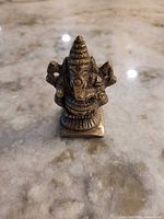 Front view of brass Ganesha figurine on marble surface