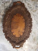 Full view of carved oval wooden tray showing handles and decorative rim