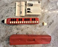 Melodica, case, extra mouthpiece, instruction leaflet displayed on surface