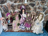 Group shot of seven dressed porcelain dolls on stands
