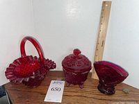 Three ruby red glass pieces with ruler for scale