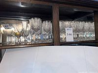 Cabinet shelf showing entire set of crystal stemware with additional commemorative tumbler and gilt coupe