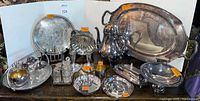 Group shot of all silverplate items including trays, tea kettle, bowls, candlesticks, cruet set
