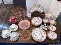 Entire assortment on table showing porcelain tea service, pink glass plates, goblets and bowls