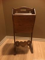 Front view of wooden magazine rack showing handle and compartment