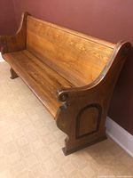 three-quarter view of full pew showing scrolled end and seat