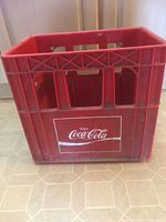 Overall view of red Coca-Cola plastic crate showing logo and compartment openings