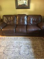 Front view of three-seat brown leather reclining sofa