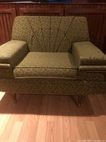 Front view of chair showing full shape, upholstery pattern, armrests, legs