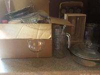 Overall view of lot showing glass pitcher, hurricane candle holders, casserole dish, muffin tin, skewers and other items